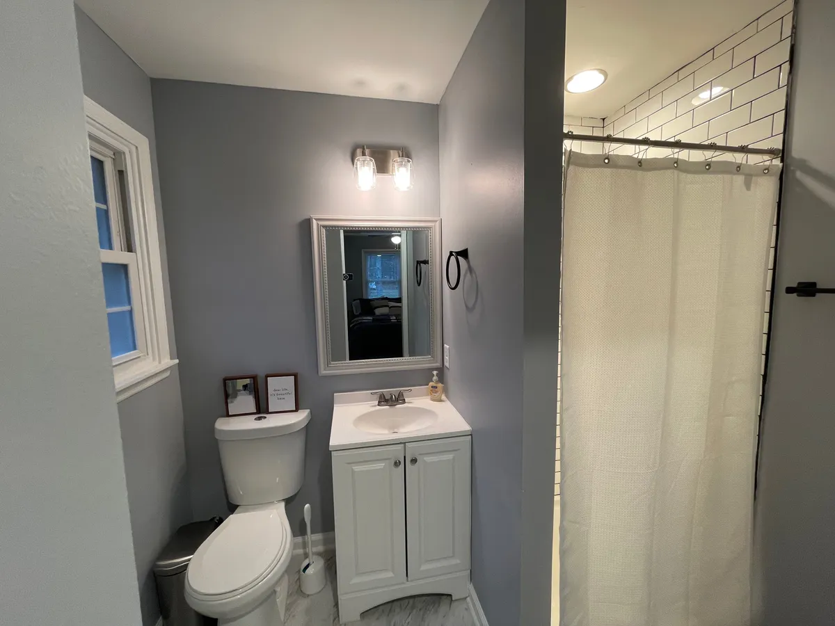 A serene bathroom featuring a modern sink, a large mirror, and a sleek shower area. The tranquil lighting and minimalist decor create an inviting and calm atmosphere, ideal for unwinding after a busy workday or refreshing in the morning.